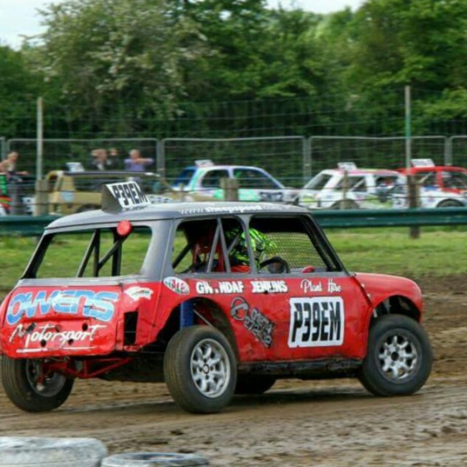 An autograss Mini race car leaning hard into a dirt track corner, showcasing chassis reliability under extreme lateral load.