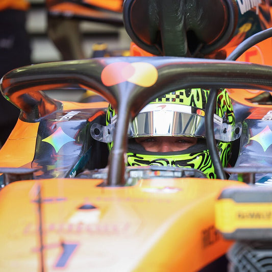 An F1 driver hunkered down inside the tight cockpit, with only their personalized racing helmet poking out over the rim.