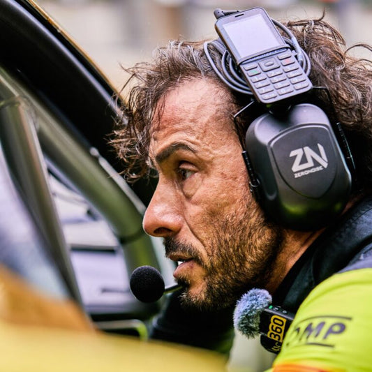 Race engineer sitting pit side on the pit wall wearing a ZeroNoise radio headset during a motorsport event.