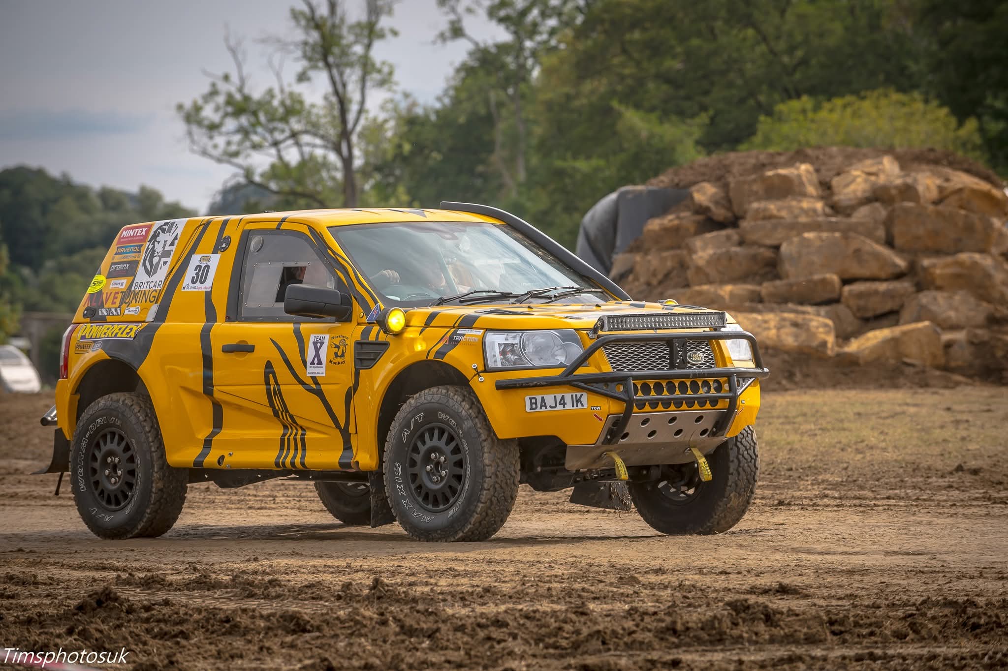 Pat Masters Yellow off-road Landrover on a dirt track with trees and rocks in the background practising for the Baja 1000